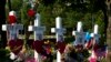 FILE - An American flag is placed next to markers representing the people killed in a newsroom shooting, at a makeshift memorial at the scene outside the office building housing The Capital Gazette newspaper in Annapolis, Md., on July 1, 2018.