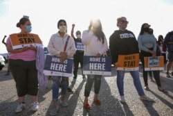 FILE - People hold signs as they take part in a rally for "Justice Everywhere" to celebrate the U.S. Supreme Court's ruling to disallow the rescinding of the Deferred Action for Childhood Arrivals (DACA) program, in San Diego, California, June 18, 2020.