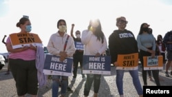 FILE - People hold signs as they take part in a rally for "Justice Everywhere" to celebrate the U.S. Supreme Court's ruling to disallow the rescinding of the Deferred Action for Childhood Arrivals (DACA) program, in San Diego, California, June 18, 2020.