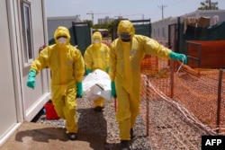 FILE - Members of medical team carry the body of a deceased COVID patient on a stretcher at a Ministry of Health Infectious Disease Unit in Juba, South Sudan, May 28, 2020.