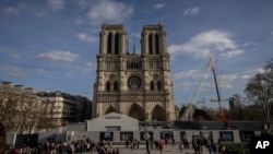 FILE - Scaffolding is being removed around the spire of Notre Dame de Paris cathedral, showing the rooster and the cross, in Paris, Feb. 17, 2024. 