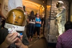 Jack Heely, 5, of Alexandria, Va., wears a toy space helmet as he arrives as one of the first visitors to view Neil Armstrong's Apollo 11 spacesuit, background, after it is unveiled at the Smithsonian's National Air and Space Museum.