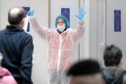 A member of a medical team gestures to indicate the number of the vaccination booth, at a Pfizer-BioNTech COVID-19 vaccination center in Bucharest, Romania, Jan. 20, 2021.