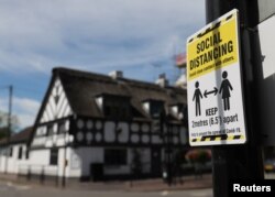 FILE - A sign promoting social distancing is hung on a post near the Crown and Anchor pub following a spike in cases of COVID-19 to visitors of the pub in Stone, Britain, July 30, 2020.