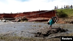 FILE: A boy near a bridge that was damaged by floods caused by torrential rain in Kasese district, 440km southwest from the capital Kampala. Taken 5.8.2013