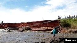 Un enfant joue près d'un pont endonnagé à cause des inondations, à Kampala, le 8 mai 2013.