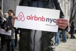 FILE - Supporters of Airbnb stand during a rally at City Hall in New York in 2015.