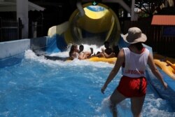 FILE - Guests ride a raft down a water slide at Golfland Sunsplash water park in Mesa, Arizona, after COVID-19 restrictions were lifted, May 15, 2020.