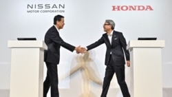 FILE - Makoto Uchida (kiri), presiden dan CEO produsen mobil Jepang Nissan, dan Toshihiro Mibe (kanan), direktur, presiden, dan pejabat eksekutif perwakilan produsen mobil Honda, berjabat tangan di awal konferensi pers di Tokyo, 1 Agustus 2024. (Richard A. Brooks / AFP)