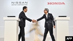 FILE - Makoto Uchida (kiri), presiden dan CEO produsen mobil Jepang Nissan, dan Toshihiro Mibe (kanan), direktur, presiden, dan pejabat eksekutif perwakilan produsen mobil Honda, berjabat tangan di awal konferensi pers di Tokyo, 1 Agustus 2024. (Richard A. Brooks / AFP)