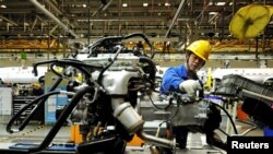 An employee works on an automobile assembly line at a factory in Qingdao, Shandong province, China, March 1, 2016. Activity in China's manufacturing sector shrank more sharply than expected in February.