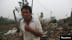 Un homme se tient sur les débris de sa maison après une tornade dans le comté de Funing, Yancheng, province du Jiangsu, en Chine, le 23 Juin, 2016.