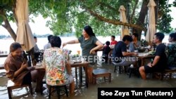 Orang-orang makan di restoran yang kebanjiran, di mana pengunjung berdiri dari meja mereka setiap kali ombak datang, di tepi sungai di Nonthaburi dekat Bangkok, Thailand, 7 Oktober 2021. (Foto: REUTERS/Soe Zeya Tun)