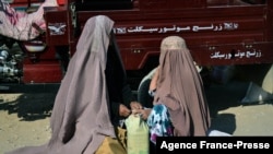 FILE - Women wearing a burqa sort food aid distributed by the Red Cross in Kandahar, Afghanistan, Dec. 15, 2021.