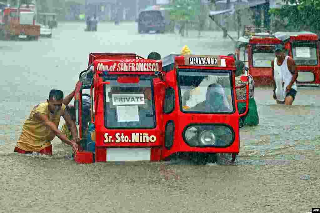 People push a half-submerged tricycle through a flooded street due to heavy rains caused by tropical depression Vicky in San Francisco town, Agusan del sur province on the southern island of Mindanao, Philippines.