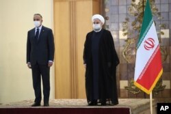 In this photo released by the official website of the office of the Iranian Presidency, President Hassan Rouhani, right, welcomes Iraqi Prime Minister Mustafa Kadhimi during an official arrival ceremony, in Tehran, Iran, July 21, 2020.