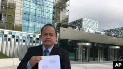 FILE - Lawyer Jude Sabio from the Philippines holds a 77-page file outside the International Criminal Court in The Hague, Netherlands, April 24, 2017. Sabio presented the file to prosecutors and asked to investigate his country's president Rodrigo Duterte for crimes against humanity for his alleged involvement in extrajudicial killings of suspected drug dealers and other crime suspects. 