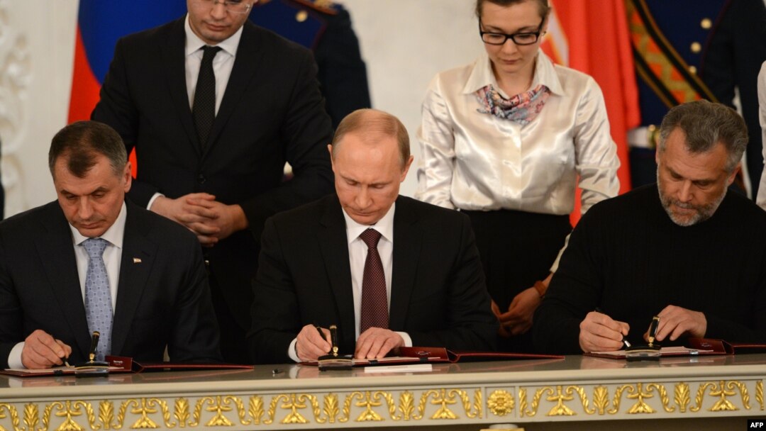 Presiden Rusia Vladimir Putin (tengah) dan para pemimpin Krimea menandatangani kesepakatan di Moskow hari Selasa (18/3). 