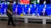 A cleaner walks past a store in Moscow with TV sets showing Russian President Vladimir Putin during his annual live call-in show, June 15, 2017.