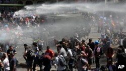 Manifestantes son rociados con un cañón de agua por la policía durante una protesta en Santiago, Chile, el miércoles 23 de octubre de 2019. Foto: AP.