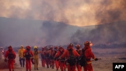 An inmate crew led by firefighters gets ready to fight the Hughes Fire as smoke fills the sky in Castaic, a northwestern neighborhood of Los Angeles County, California, Jan. 22, 2025.