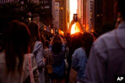 İnsanlar, Manhattanhenge gün batımını 42. caddeden fotoğraflıyor- 11 Temmuz 2022