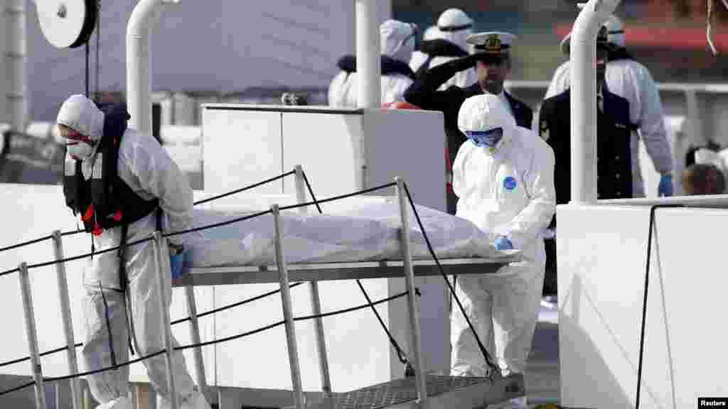 Des agents de la Garde côtière italienne, couverts de vêtements de protection, transportent le corps d&#39;un immigrant mort, hors de leur navire Bruno Gregoretti, à Senglea, à La Valette Grand Harbor, le 20 avril 2015.