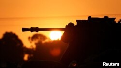 FILE - An armoured personnel carrier (APC) is seen silhouetted as the sun sets, amid the conflict between Israel and the Palestinian Islamist group Hamas, near the Israel-Gaza border, in Southern Israel, December 25, 2023.