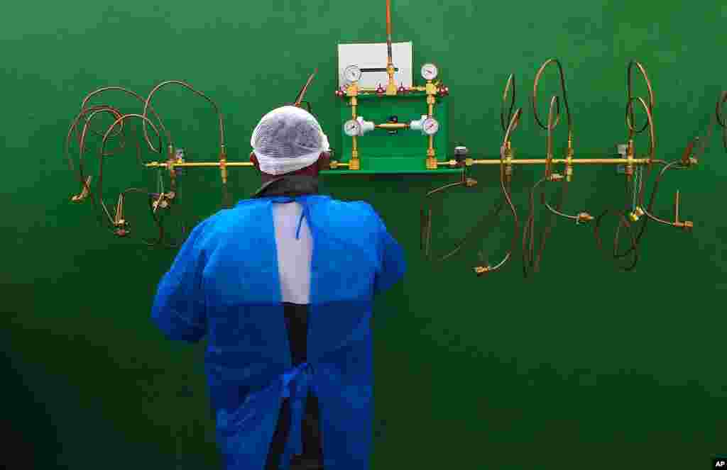 A health worker stands in front of an empty oxygen tank station, the only station at Joventina Dias Hospital, a small clinic in Manaus, Brazil.