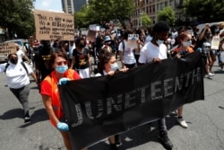 People carry a banner as they take part in events to mark Juneteenth, which commemorates the end of slavery in Texas, two years after the 1863 Emancipation Proclamation freed slaves elsewhere in the United States