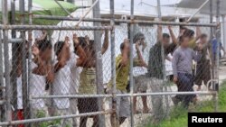 Para pencari suaka mengamati dari balik pagar di pusat penahanan di Pulau Manus, Papua Nugini, 21 Maret 2014 (Foto: dok). 