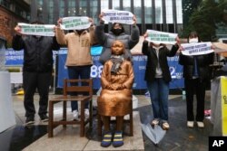 Para demonstran mengacungkan poster dalam demo untuk memperingati Hari Gerakan Kemerdekaan 1 Maret menentang penjajahan Jepang di dekat Kedutaan Besar Jepang di Seoul, Korea Selatan, 1 Maret 2021. (Foto: Ahn Young-joon/AP Photo)