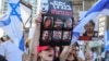 (FILE) A protester lifts a placard bearing portraits of six Israeli hostages whose bodies were recovered by the army from the southern Gaza Strip, during a rally by families and supporters of the hostages in Tel Aviv on September 2, 2024.