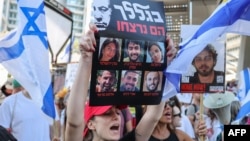 (FILE) A protester lifts a placard bearing portraits of six Israeli hostages whose bodies were recovered by the army from the southern Gaza Strip, during a rally by families and supporters of the hostages in Tel Aviv on September 2, 2024.