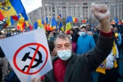 A man shouts slogans outside the government headquarters during a protest against the COVID-19 pandemic restrictions in Bucharest, Romania, April 3, 2021.