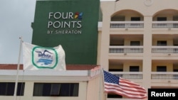 Un drapeau américain et un drapeau de la compagnie militaire cubaine flottent près du logo d'un hôtel" Four Points by Sheraton " à La Havane , Cuba , le 27 Juin , ici 2016.