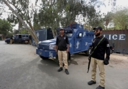 Police officers guard a road blocked with shipping containers, near the French consulate, in Karachi, Pakistan, April 15, 2021.