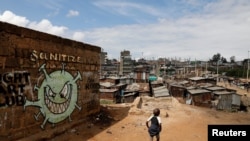 FILE - A boy walks in front of a graffiti promoting the fight against the coronavirus disease, in the Mathare slums of Nairobi, Kenya, May 22, 2020. Kenya reimposed some COVID-19 lockdown restrictions on March 26, 2021. 