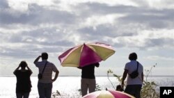 People look out to sea from a hill top after an alert of tsunami was launched in Hanga Roa, Easter Island, Chile, March 11, 2011