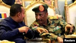 Sudan's Gen. Abdel Fattah Burhan talks to Ethiopia's Prime Minister Abiy Ahmed during the signing of a power-sharing deal in Khartoum, Sudan, Aug. 17, 2019.