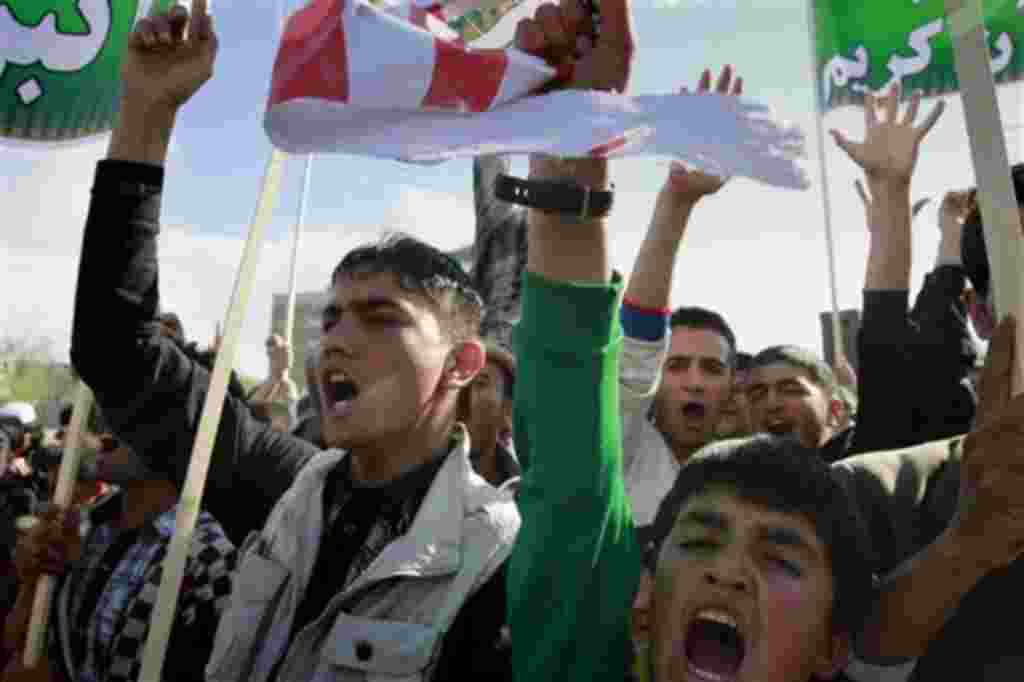 Afghans shout anti- US slogans, as a protester holds a piece of US flag during a demonstration in Kabul, Afghanistan on Friday, April. 1, 2011. Eight foreigners were killed on Friday after demonstrators protesting a reported burning of the Muslim holy b