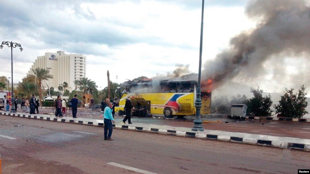 Security officials and onlookers are seen at the site of a tourist bus blast in the Egyptian south Sinai resort town of Taba Feb. 16, 2014.