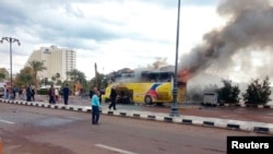 Security officials and onlookers are seen at the site of a tourist bus blast in the Egyptian south Sinai resort town of Taba Feb. 16, 2014.