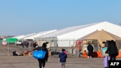 FILE - Migrants who arrived a few days ago from Eagle Pass, Texas, walk to the shelters at Floyd Bennett Field in the Brooklyn borough of New York on Feb. 3, 2024.