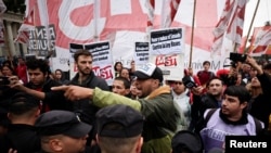 Un hombre reacciona junto a agentes de policía, mientras la gente participa en una marcha durante las celebraciones del Primero de Mayo, en Buenos Aires, Argentina, el 1 de mayo de 2024.May Day celebrations in Buenos Aires.