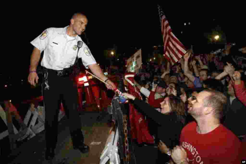 A U.S. Park Police officer is handed a flag as crowds celebrate on Pennsylvania Avenue in front of the White House in Washington, early Monday, May 2, 2011, after President Barack Obama announced that Osama bin Laden had been killed (AP Photo/Charles Dhar