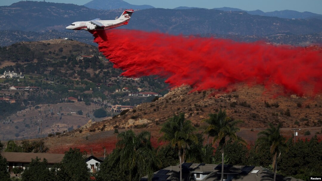 Sebuah pesawat berusaha memadamkan kebakaran di kota Bonsall, California selatan hari Jumat (8/12). 