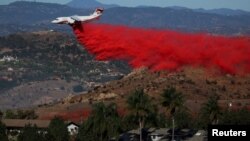 Sebuah pesawat berusaha memadamkan kebakaran di kota Bonsall, California selatan hari Jumat (8/12). 