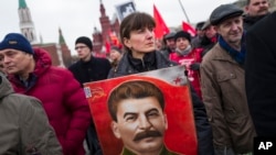 FILE - Communist party supporters hold portraits of Stalin as they line up to place flowers on his grave in Red Square, outside the Kremlin wall, to mark the 64th anniversary of his death in Moscow, Russia, March 5, 2017. Polls show that Stalin is being increasingly seen by Russian as less a villain and more of an "effective manager" and a symbol of Soviet-Russian power.