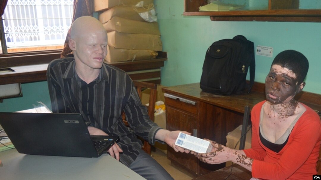 Mary Jana (right) one of few patients who collect sunsecreen from Simbota (left) dspites reports of kidnappings and killings. (Lameck Masina for VOA News)